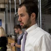 An alumnus holding a drink, watching the game at the Fowling Fun Event